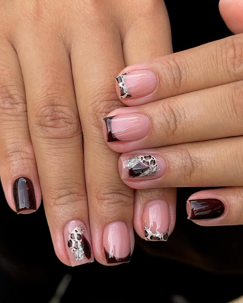 Short nails with brushed chocolate tips, leopard print accents, and silver glitter on a sheer pink base
