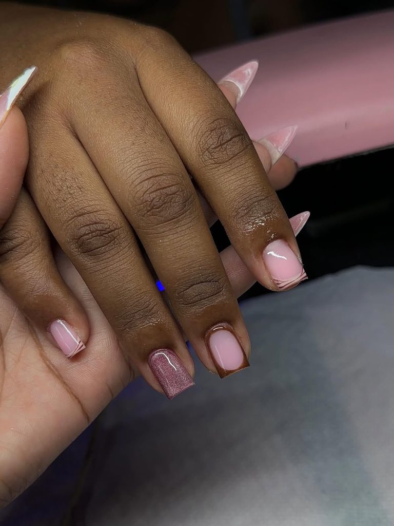 Short square nails with sheer pink base, chocolate outline, and mauve shimmer accent on deep skin tone